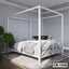 Modern white canopy bed frame in a contemporary bedroom on a striped rug with plants nearby
