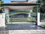 Decorative metal boundary gate with gold accents in front of a modern house