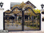 Decorative black and gold metal boundary gate with ornate patterns at a residential entrance