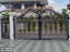 Decorative wrought iron boundary gate with gold floral designs in front of a house