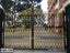 Decorative black and gold wrought iron gate with intricate patterns, installed outdoors.