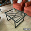 Modern glass center table with black metal frame in a living room setting