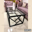 Modern glass center table with black metal frame in living room with pink sofas
