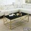 Modern gold metal and black glass center table in a living room with white sectional sofa
