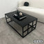Modern black glass center table with metal frame in a minimalist living room setting