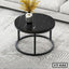 Modern round black center table with metal frame, marble top, and vase on a striped rug