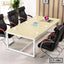 Modern conference table with six black office chairs, laptop, books, and coffee cups in meeting room.