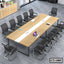 Modern conference room with large rectangular meeting table, black office chairs, and devices