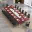 Large modern conference table with chairs, laptops, papers, and green plants in office setting