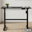 Electric folding desk with black frame, laptop, notebook, and potted plant in home office