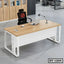 Modern executive office table with light wood top, white base, office chair, and workspace accessories