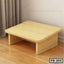 Wooden foot rest for office or home, light finish, placed on wooden floor by curtain.