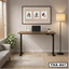 Modern home office with electric adjustable desk, laptop, indoor plant, and wall art