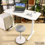 Modern white computer desk with laptop and gray stool in a home office setting