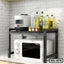 Modern black metal kitchen shelf holding microwave, rice cooker, oil bottles, and spices
