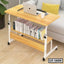 Modern wooden laptop table with shelves on wheels, holding books, beside a sofa in a home office.