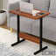 Wooden laptop table with black metal legs beside a grey sofa, ideal for home or office use.