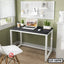 Modern minimalist laptop table with metal frame, black top, chair, and indoor plants in home office setting