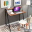 Modern wooden laptop table with black metal frame and white chair in home office setting