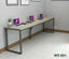 Modern office desk with metal frame, four laptops, notebooks, and minimalist decor in a workspace.