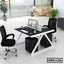 Modern office workstation with dual black mesh chairs, computer monitors, drawers, and city view