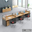 Modern office workstation with three desks, black chairs, wooden drawers, and laptops