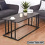 Modern rectangular center table with black metal frame, potted plant, and candles in a living room.