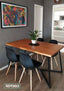 Modern dining area with a wooden table, four black chairs, potted plant centerpiece, and wall art.