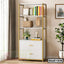 Modern white and gold bookshelf with drawers, books, decor, and plants in a bright living room