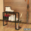 Modern metal shoe rack with boots, sneakers, umbrella and wooden floor background