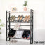 Modern black metal shoe rack with multiple shelves holding various shoes, houseplant and decor on top