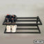 Two-tier black metal shoe rack with sneakers and loafers on a light background