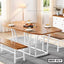 Modern wooden dining table with steel legs and benches, set for a meal in a bright dining room