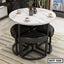 Modern round marble dining table with steel frame and four black cushioned stools in a living room.