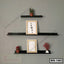 Modern black wall shelf set with picture frames, small potted plants, and decorative items
