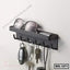 Wall-mounted black metal shelf with hooks holding keys, sunglasses, and small items.