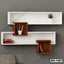 Modern wall shelf with white and brown geometric design, books, plant, and decor on a gray wall