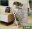 Modern white and wood plant stand with glass vase of red roses and green potted plant in living room