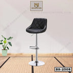 Modern black leather bar stool with chrome base and footrest in a minimal indoor setting