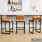 Set of three modern bar stools with tan cushioned seats and black metal frames in a home kitchen