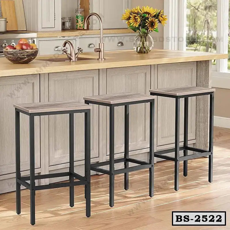 Set of three modern bar stools with black metal frames and wooden seats in a kitchen setting