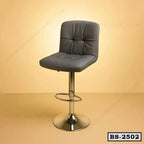Modern black leather bar stool with metal base and footrest against a beige background