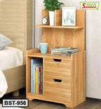 Wooden bedside table with storage drawers, books, shelf, and decor by a bed