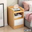 Modern wooden bedside table with open shelves and one white drawer beside a bed