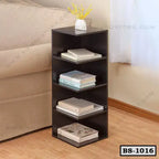 Modern dark wood bookshelf with four shelves, books, and vase, next to beige sofa