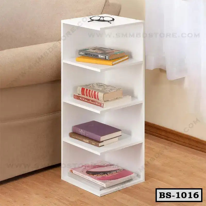 White modern bookshelf with four shelves, holding books, beside a beige sofa on wooden floor