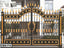 Elegant black and gold boundary gate with decorative spikes and accents, installed at a modern house entrance.