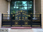Modern black metal boundary gate with gold floral and geometric designs, placed outdoors.
