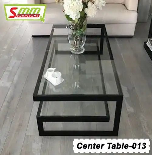 Modern glass coffee table with black metal frame, flower vase, and decorative tray in living room