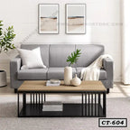 Modern center table with wooden top and black metal frame in a living room with grey sofa.